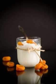 homemade sweet yogurt in a glass with dried apricots isolated on black background