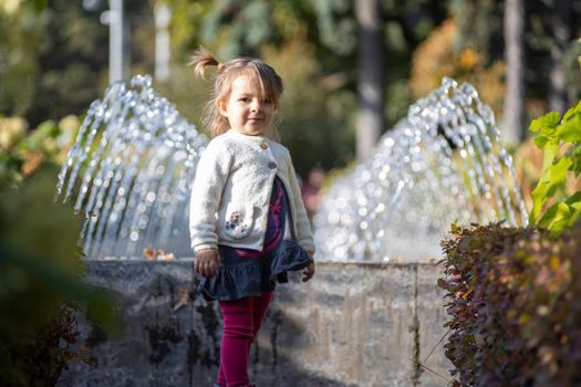 charming toddler in the park with fountains in the background. summer day