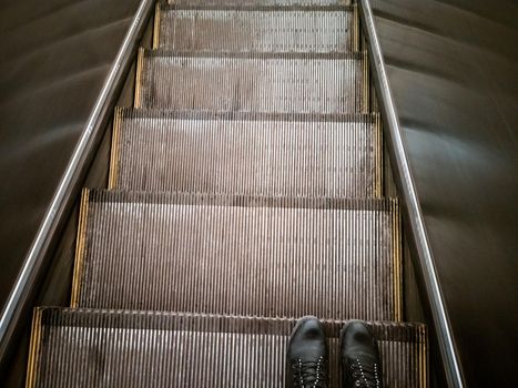feet on the escalator top view. a human rides an escalator down the subway