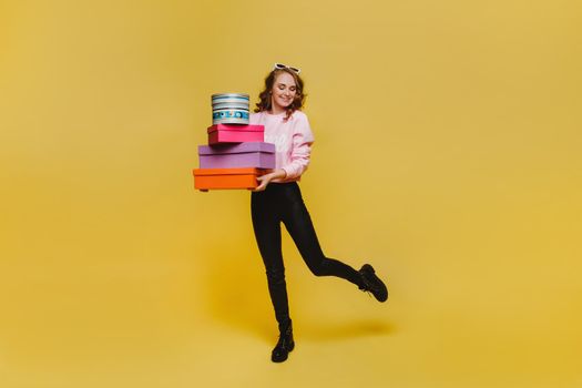 Beautiful young woman holding an big gift box. Attractive elegant young woman holding gift box over red background. Pretty birthday girl wearing make up and elegant clothes