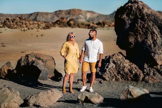 a couple, a woman and a man in the desert crater of the Teide volcano and enjoy the sunset view. Travel to the mountains, freedom and the concept of an active lifestyle.Canary Islands, Spain.