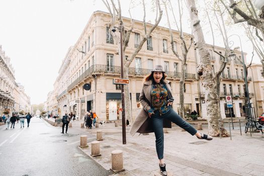 a beautiful romantic girl in a coat with her hair down runs through the old city of Avignon. France. Girl in a coat in France.