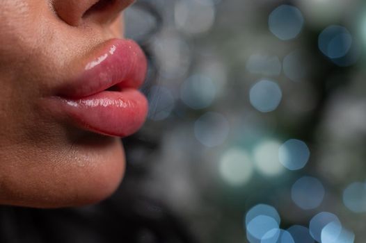 Close-up of large plump female lips against a background of christmas decorations