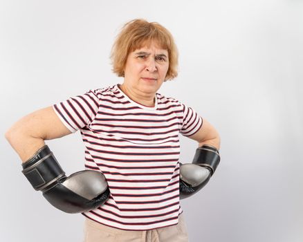 Elderly woman in fighting gloves in a defensive pose on a white background