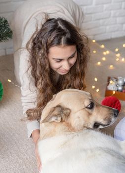 Merry christmas and happy new year. young attractive woman decorating the Christmas tree and playing with dogs