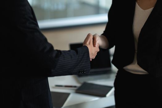 Business people handshake at meeting table in office together with confident . Young businessman and businesswoman workers express agreement of investment deal.