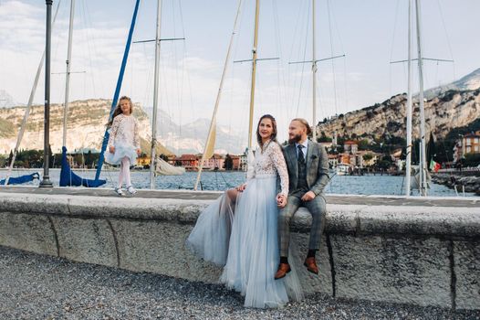 Italy, Lake Garda. Beautiful family on the shores of lake Garda in Italy at the foot of the Alps. Father, mother and daughter in Italy.