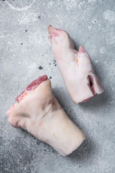 Raw pork hoof, feet, trotters on a butcher board. Gray background. Top view.