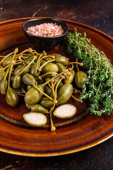 Pickled Capers berries in a rustic plate. Dark background. Top view.