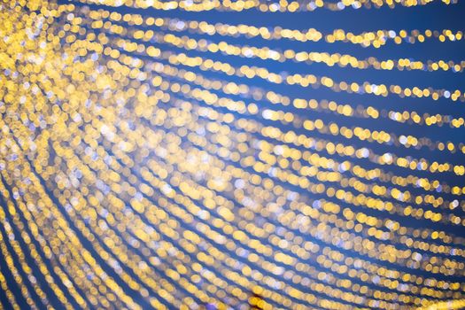 Christmas holiday background, shining garland in the blue evening frozen sky at New Year's street marketplace fair in blur