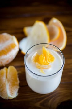 homemade sweet yogurt in a glass with oranges on a wooden table