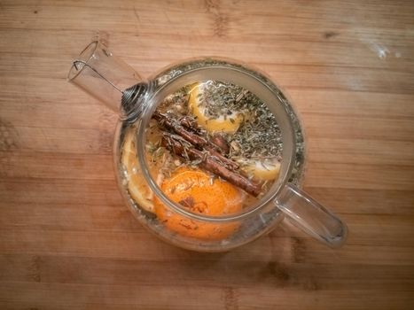 citrus tea with cinnamon in a glass teapot top view on wooden table
