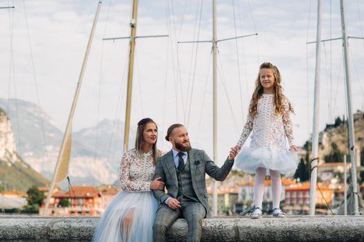 Italy, Lake Garda. Beautiful family on the shores of lake Garda in Italy at the foot of the Alps. Father, mother and daughter in Italy.