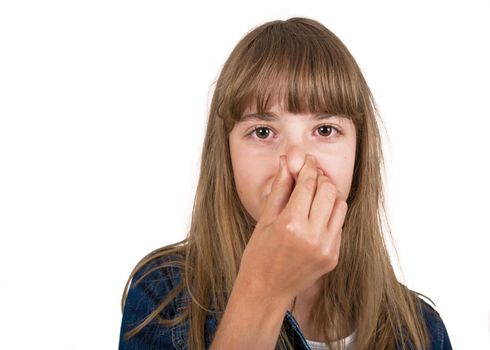 Little girl in checked brown shirt pinching her nose because of bad smell.