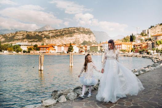 Italy, Lake Garda.Stylish Mother and daughter on the shores of lake Garda in Italy at the foot of the Alps. mother and daughter in Italy.