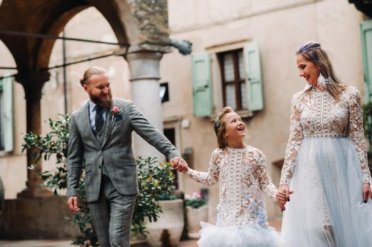 A happy young family walks through the old town of Sirmione in Italy.Stylish family in Italy on a walk.