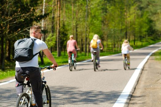 A group of cyclists with backpacks ride bicycles on a forest road enjoying nature.