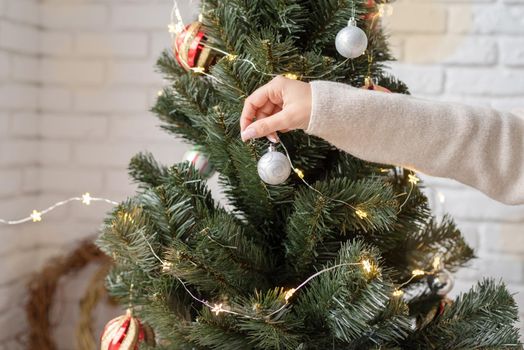 Merry christmas and happy new year. woman decorating the Christmas tree with fairy lights