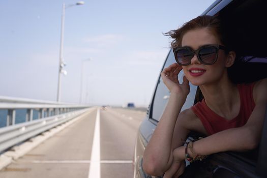 a woman is driving in a car on the road and looking out of the window. High quality photo