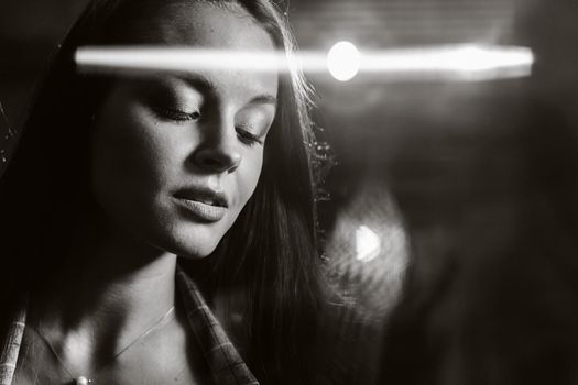 Portrait of a young European girl with long hair in a coffee shop in the evening light, a tall Girl in a jacket with long hair in a cafe. black and white photo.