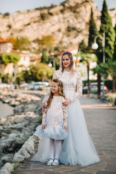 Italy, Lake Garda.Stylish Mother and daughter on the shores of lake Garda in Italy at the foot of the Alps. mother and daughter in Italy.