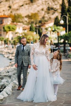 Italy, Lake Garda. Beautiful family on the shores of lake Garda in Italy at the foot of the Alps. Father, mother and daughter in Italy.