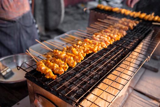 chicken satay grilled on grills plate with smoke. asian street food