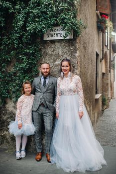 A happy young family walks through the old town of Sirmione in Italy.Stylish family in Italy on a walk.