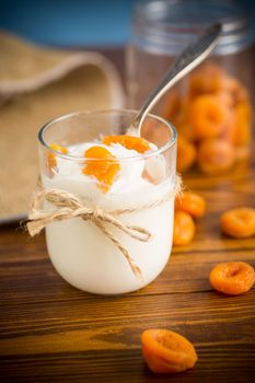 homemade sweet yogurt in a glass with dried apricots on a wooden table