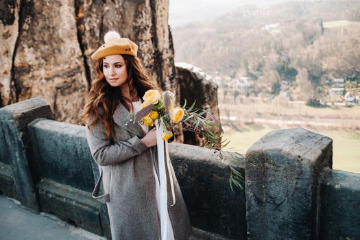 a girl in a pink dress and hat with a bouquet of flowers against the background of mountains and gorges in Swiss Saxony, Germany, Bastey.