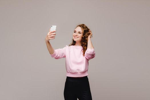 Portrait of a young attractive woman making selfie photo on smartphone isolated on a white background.