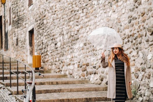 beautiful romantic girl in a coat and hat with a transparent umbrella in Annecy. France. The girl in the hat in France.
