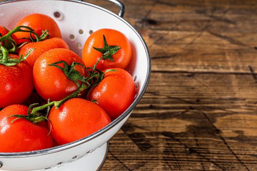 Branch of Red cherry tomatoes in colander. Wooden background. Top view. Copy space.