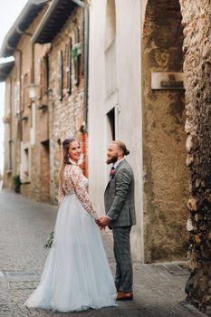 Beautiful family with walks in the old town of Sirmione in Italy.A couple strolling through old Italy.