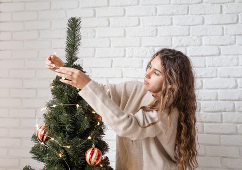 Merry christmas and happy new year. young attractive woman decorating the Christmas tree with fairy lights