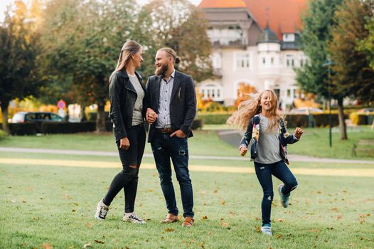 A happy family of three runs through the grass in Austria's old town.A family walks through a small town in Austria.Europe.Velden am werten Zee.