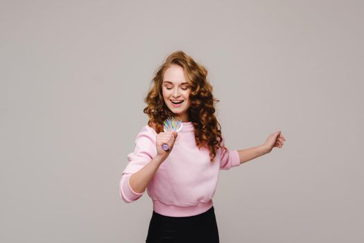 joyful girl sings into a microphone. Girl fooling around and using a comb instead of a microphone.