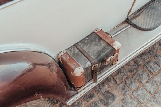 Close up of a vintage brown leather suitcase, used as a tool case on the back of a retro car