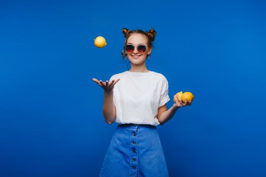 Young beautiful smiling women with curly hair tasting sour lemon halves emotionally. Funny girl with wavy hairstyle and bright make up isolated over yellow background. Copy space. Yellow lifestyle