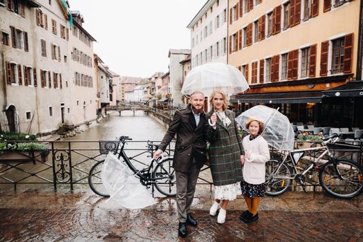 Beautiful family with umbrellas in rainy weather in Annecy. France.Family walk in the rain.