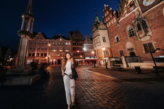 a romantic girl walks in the old town of Wroclaw in the late evening.Walk of a woman in trousers and jacket in the old town of Poland.