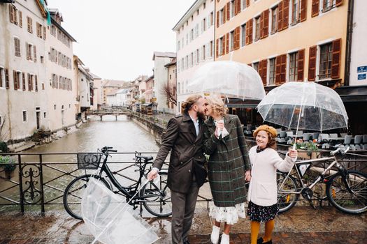 Beautiful family with umbrellas in rainy weather in Annecy. France.Family walk in the rain.