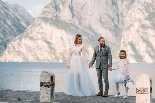 Italy, Lake Garda. Beautiful family on the shores of lake Garda in Italy at the foot of the Alps. Father, mother and daughter in Italy.