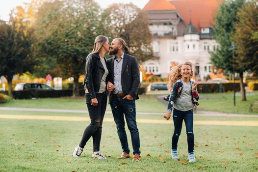 A happy family of three runs through the grass in Austria's old town.A family walks through a small town in Austria.Europe.Velden am werten Zee.