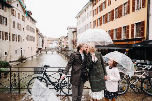 Beautiful family with umbrellas in rainy weather in Annecy. France.Family walk in the rain.