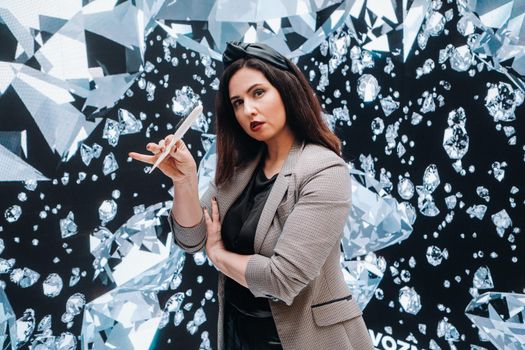 A girl in black trousers and a jacket with a comb on a background of diamonds.