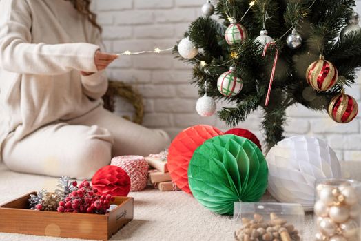 Merry christmas and happy new year. young attractive woman decorating the Christmas tree with fairy lights