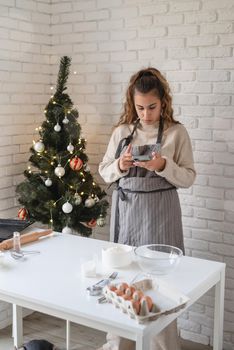 Merry christmas and happy new year. Smiling woman in the kitchen baking christmas cookies, searching for the recipe