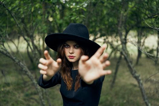 woman in black witch costume in forest nature posing. High quality photo