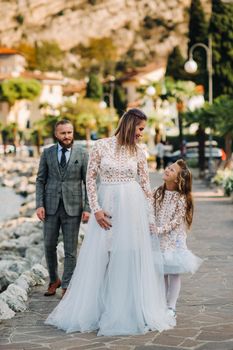 Italy, Lake Garda. Beautiful family on the shores of lake Garda in Italy at the foot of the Alps. Father, mother and daughter in Italy.